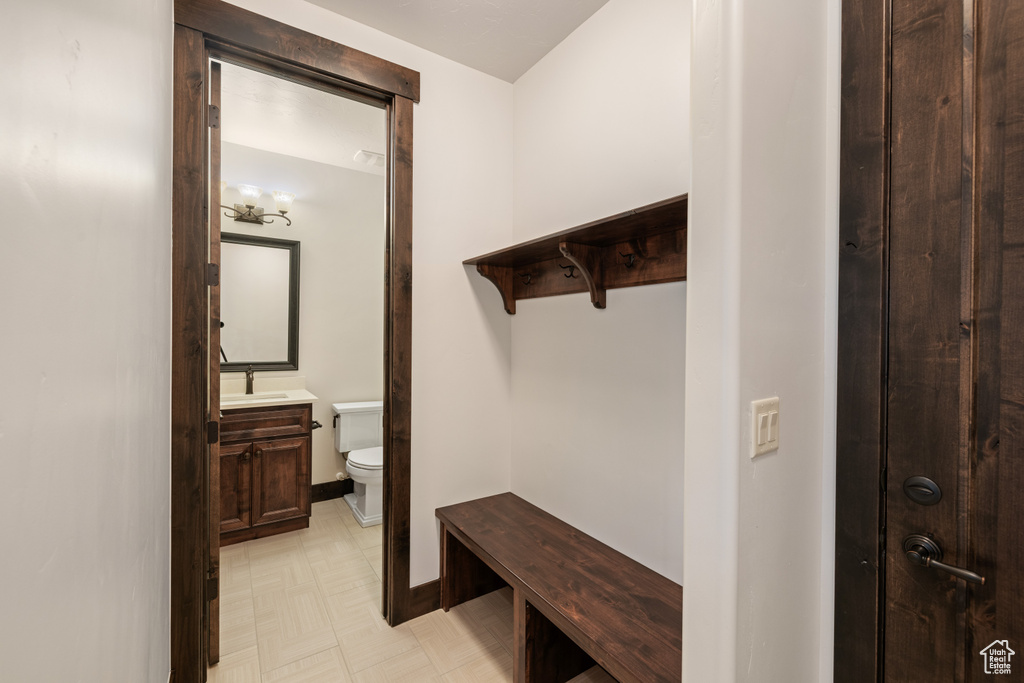 Mudroom with a sink, light floors, and baseboards