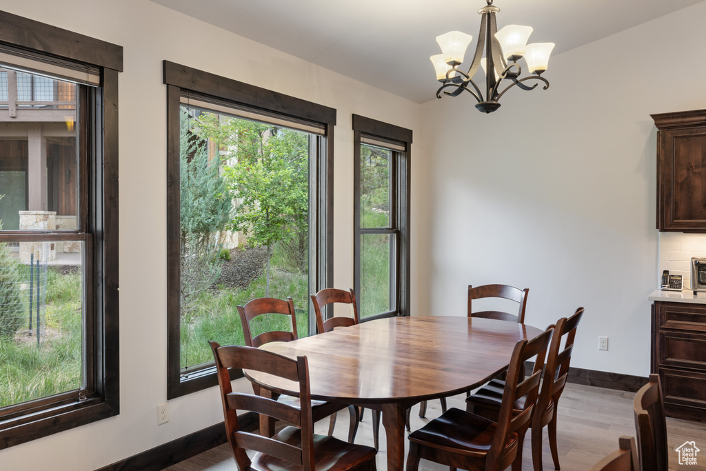 Dining space with wood finished floors, healthy amount of natural light, and a chandelier
