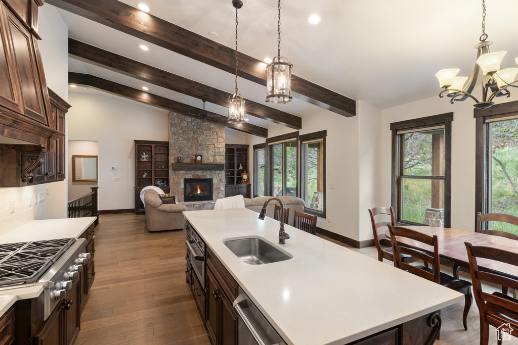 Kitchen with a sink, a chandelier, light countertops, dark brown cabinets, and a fireplace