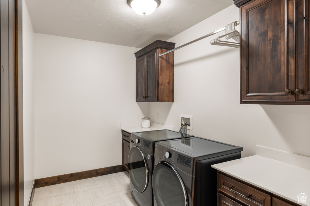 Washroom featuring cabinet space, washer and clothes dryer, and baseboards