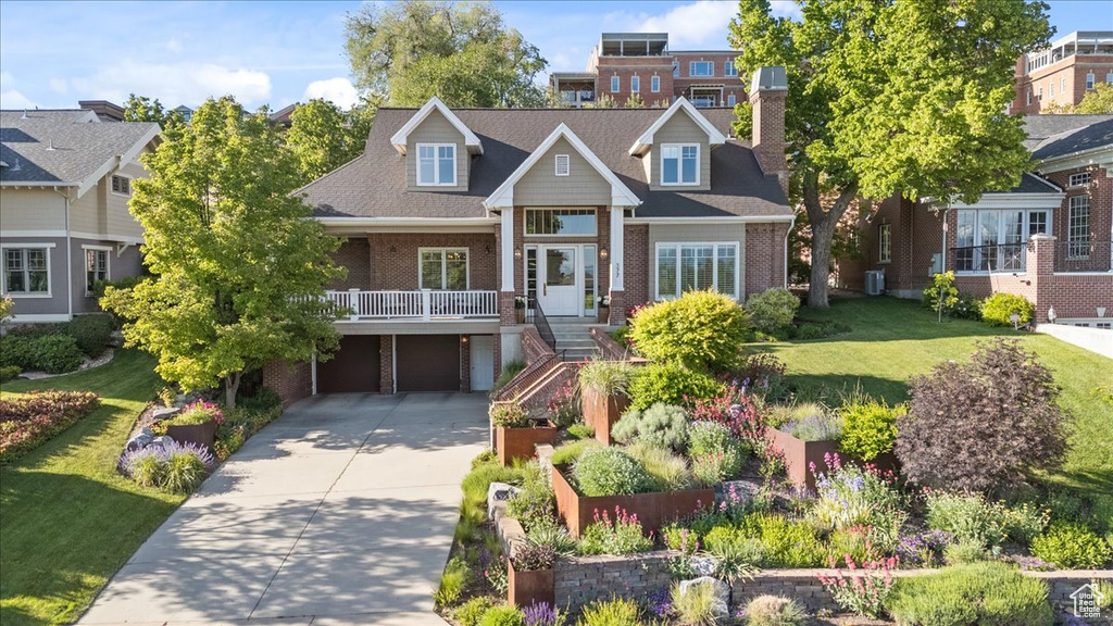 View of front of house featuring brick siding, an attached garage, driveway, and a chimney