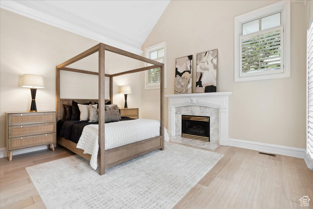 Bedroom with wood finished floors, a fireplace, baseboards, and vaulted ceiling