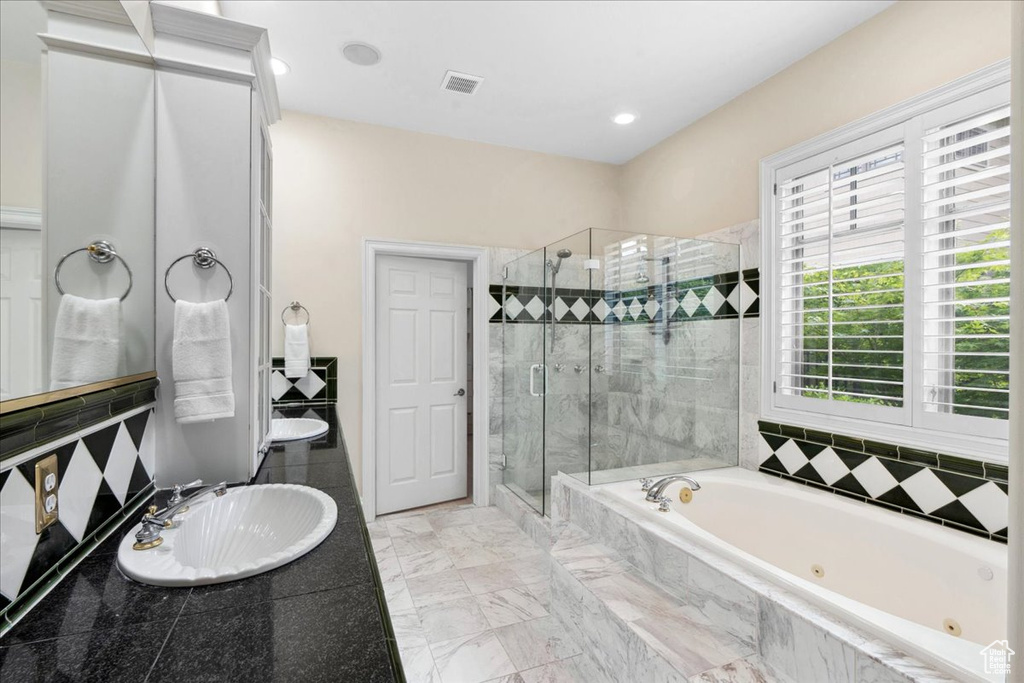 Bathroom featuring a sink, a stall shower, a tub with jets, and recessed lighting