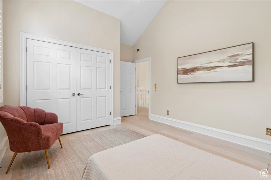 Bedroom with a closet, vaulted ceiling, light wood-style floors, and baseboards