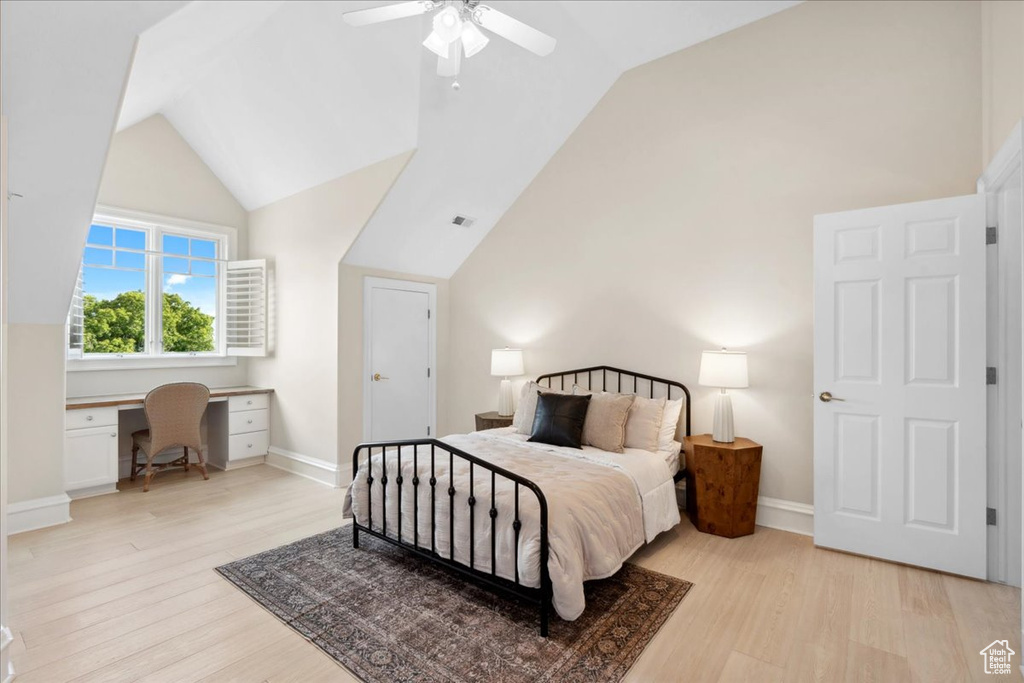 Bedroom featuring vaulted ceiling, light wood-style floors, an office area, baseboards, and ceiling fan