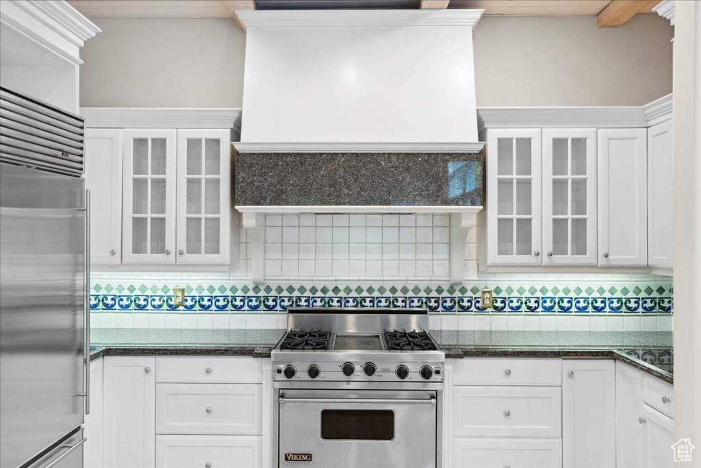 Kitchen with premium appliances, white cabinetry, and tasteful backsplash