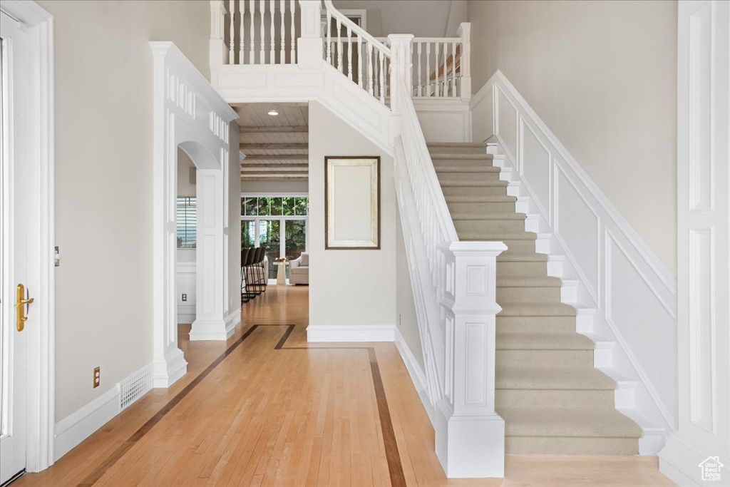 Stairway with wood-type flooring, baseboards, and arched walkways