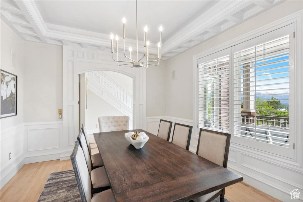 Dining space featuring a chandelier, a decorative wall, light wood-type flooring, and wainscoting
