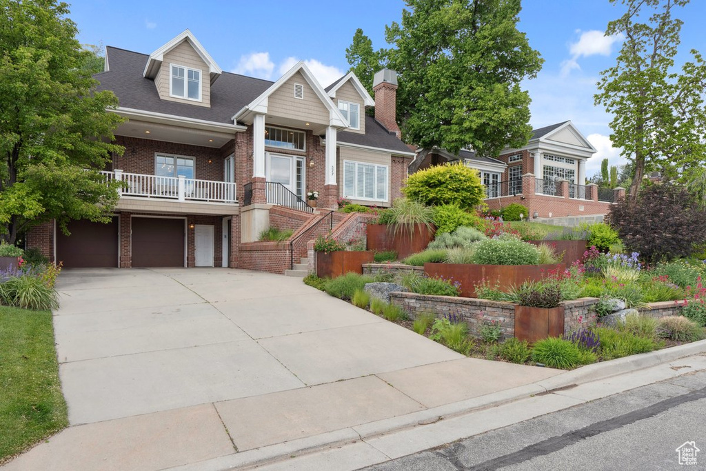 View of front of house featuring brick siding, driveway, an attached garage, a chimney, and stairway