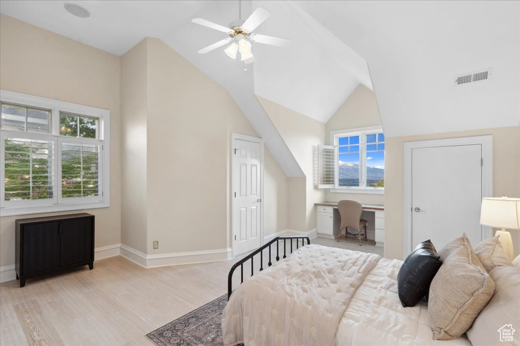 Bedroom featuring multiple windows, wood finished floors, baseboards, lofted ceiling, and a desk