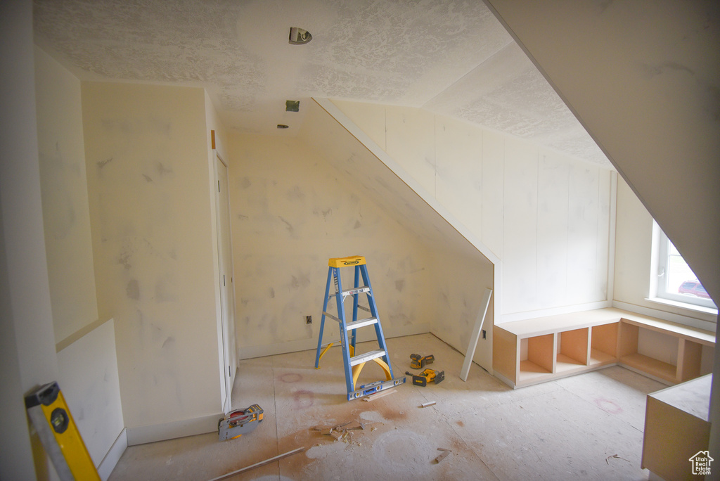 Bonus room with a textured ceiling and vaulted ceiling