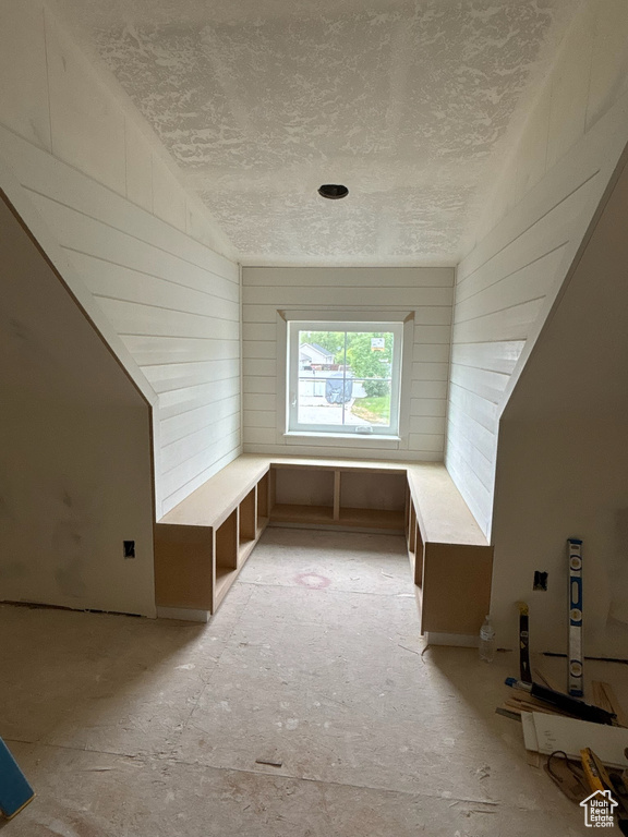 Bonus room featuring a textured ceiling and wooden walls