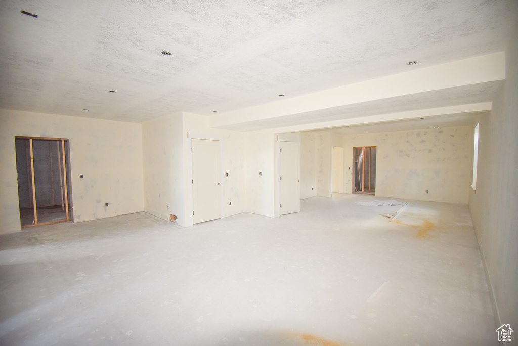 Empty room featuring unfinished concrete flooring and a textured ceiling