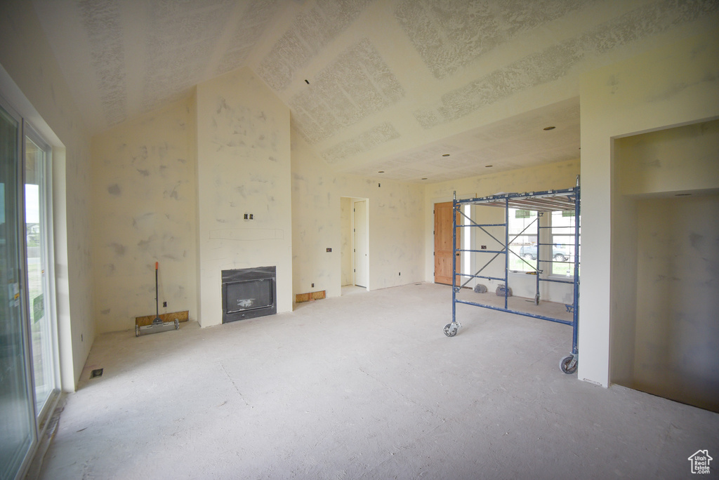 Unfurnished living room featuring a fireplace, high vaulted ceiling, and carpet