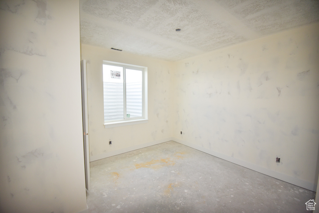 Empty room with a textured ceiling and baseboards