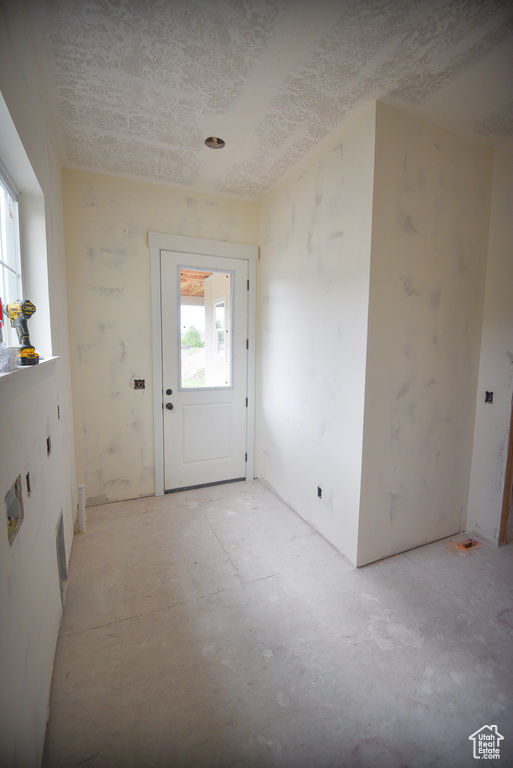 Doorway to outside with a textured ceiling