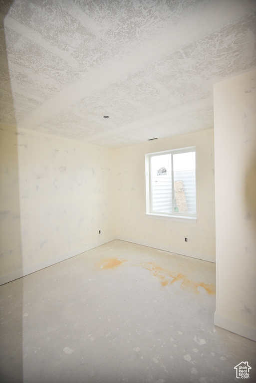 Empty room with a textured ceiling and baseboards