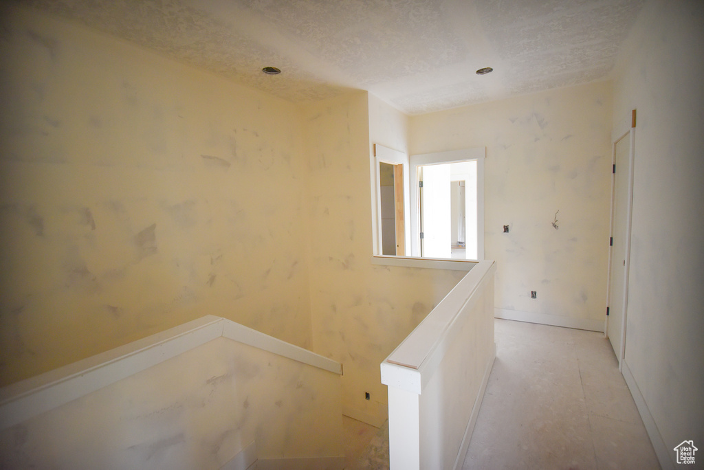 Hall with a textured ceiling and an upstairs landing