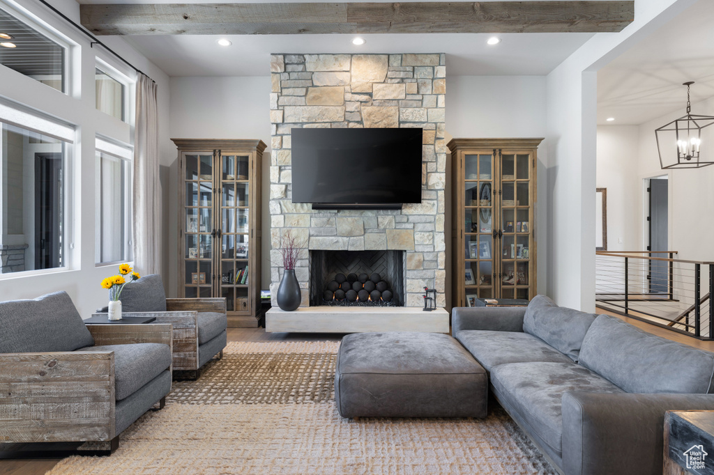 Living room with beamed ceiling, a chandelier, and a stone fireplace