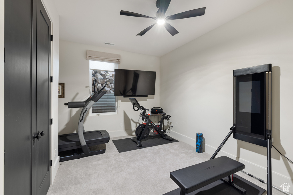 Exercise room featuring ceiling fan, baseboards, and carpet