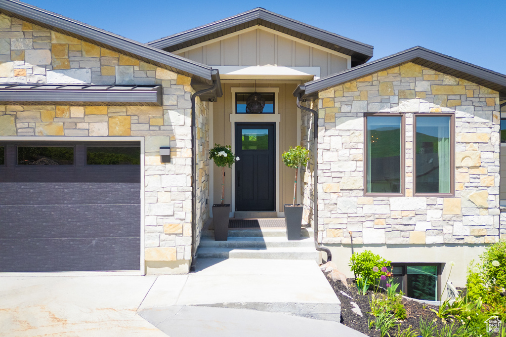 Doorway to property with stone siding, board and batten siding, and a garage