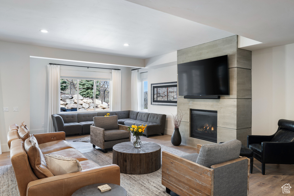 Living room with light wood finished floors, a tile fireplace, and recessed lighting