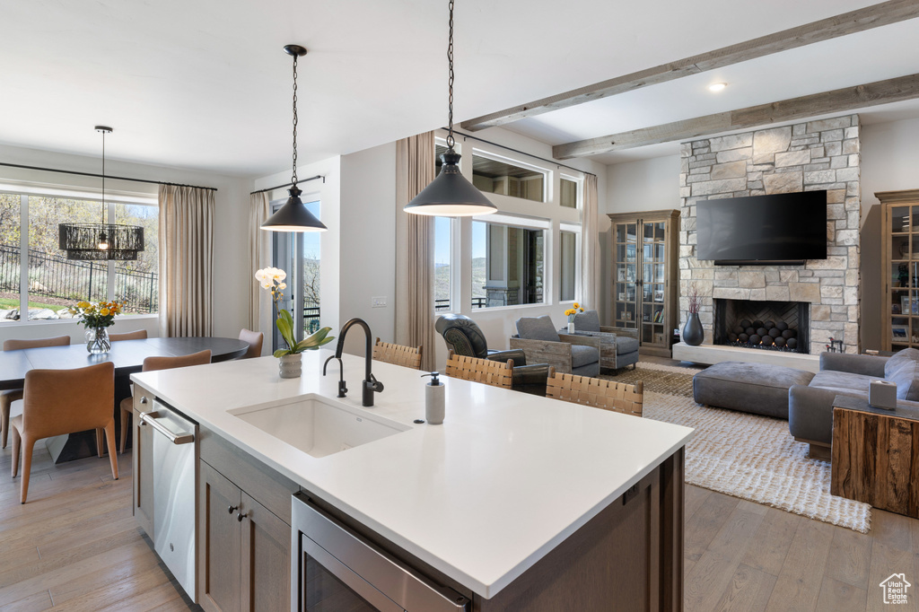 Kitchen with a sink, light wood-type flooring, a chandelier, decorative light fixtures, and beamed ceiling