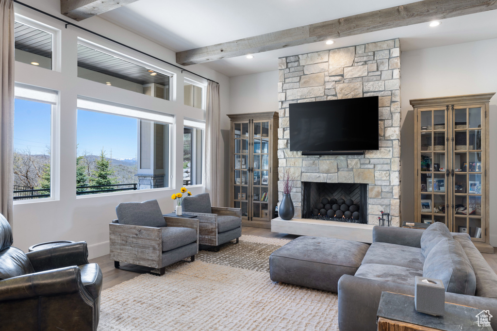 Living room with beam ceiling, wood finished floors, healthy amount of natural light, a fireplace, and recessed lighting