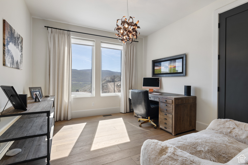 Office area with a chandelier, light wood-style flooring, and baseboards