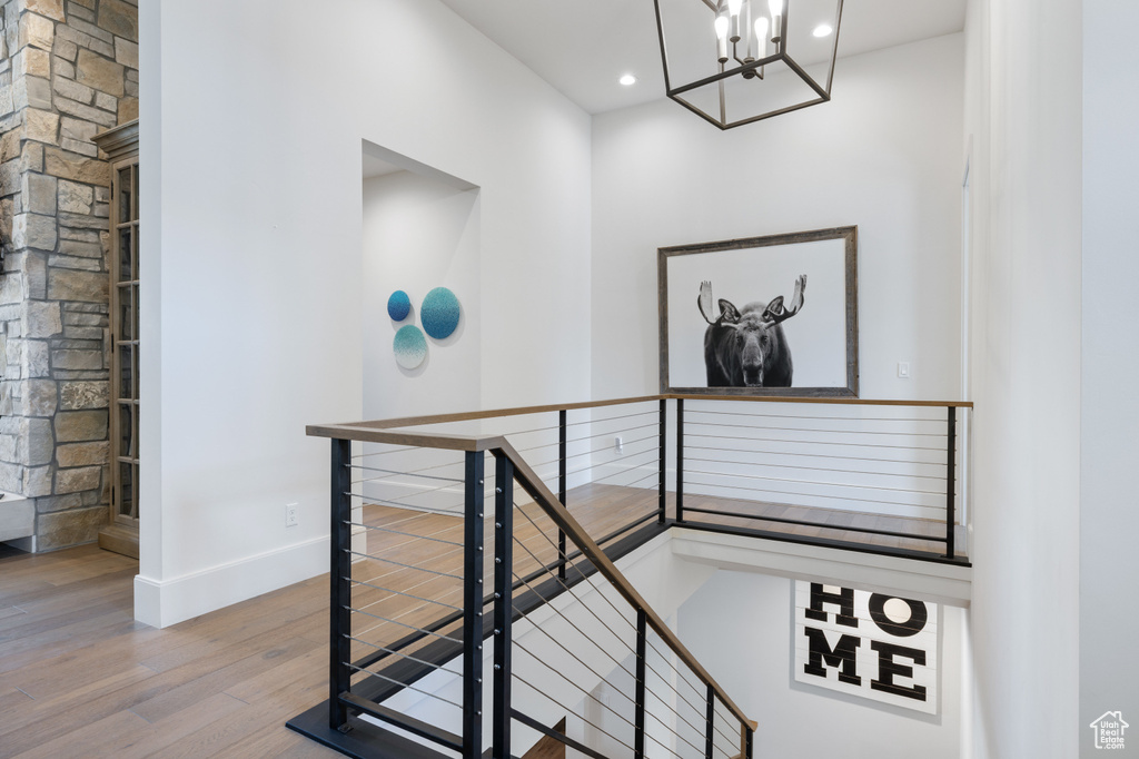 Stairway with wood finished floors, baseboards, a chandelier, and recessed lighting