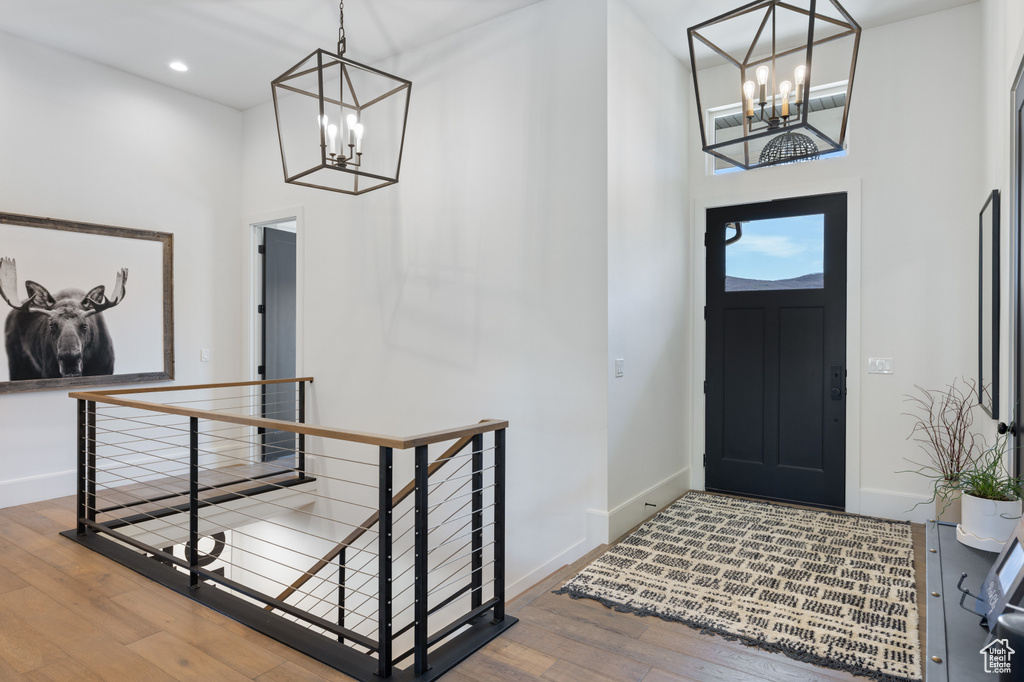 Entrance foyer featuring a chandelier, a high ceiling, baseboards, wood-type flooring, and recessed lighting