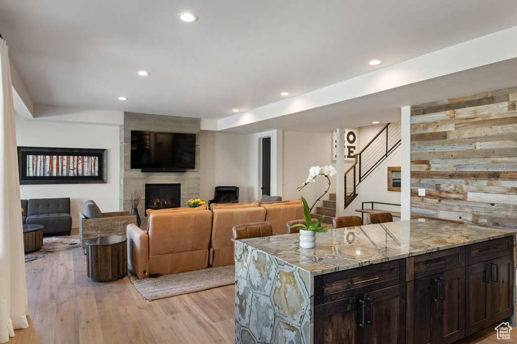 Living room featuring a large fireplace, light wood finished floors, stairway, and recessed lighting
