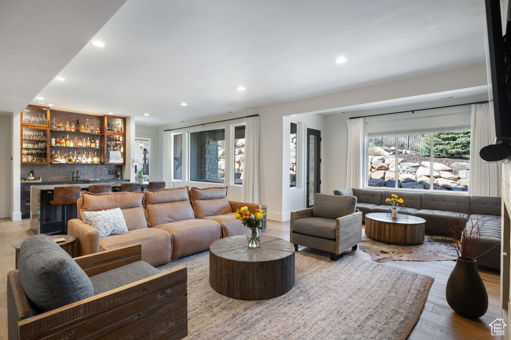 Living room with bar with sink, recessed lighting, and wood finished floors