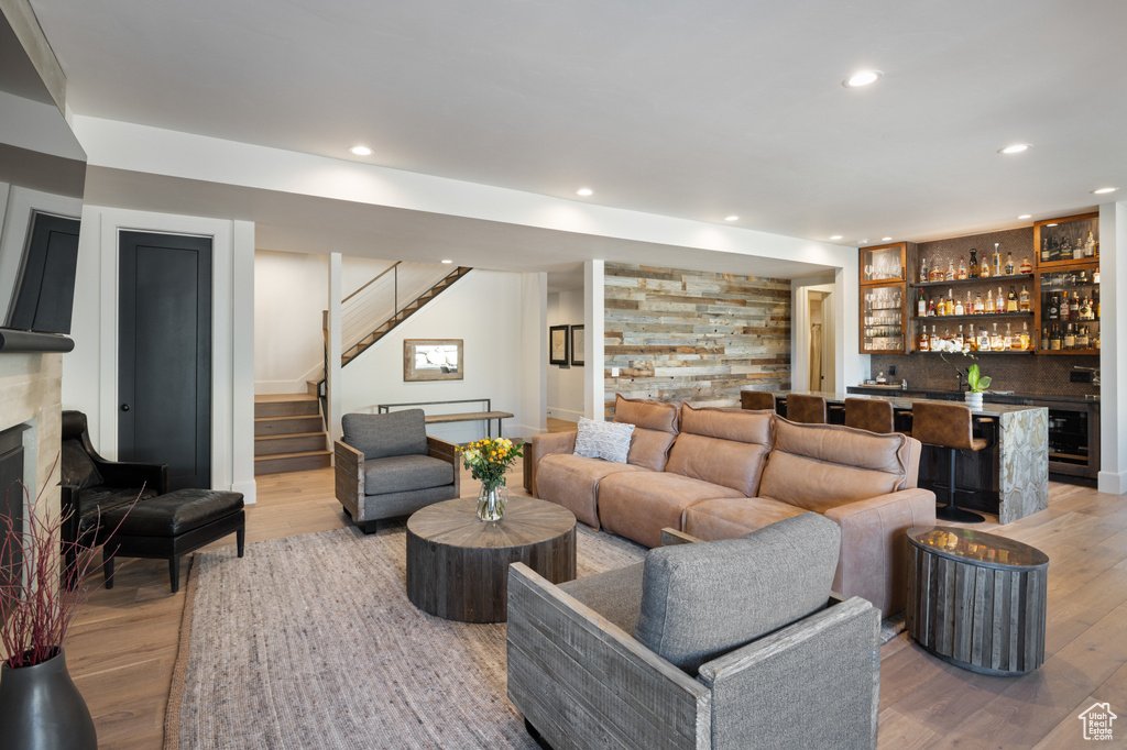 Living room featuring bar, stairs, recessed lighting, light wood-type flooring, and a fireplace