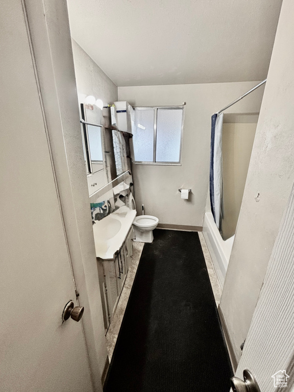 Bathroom featuring toilet, vanity, shower / bath combo, and baseboards