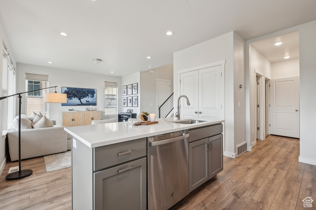 Kitchen with dishwasher, gray cabinets, a sink, light wood finished floors, and light countertops