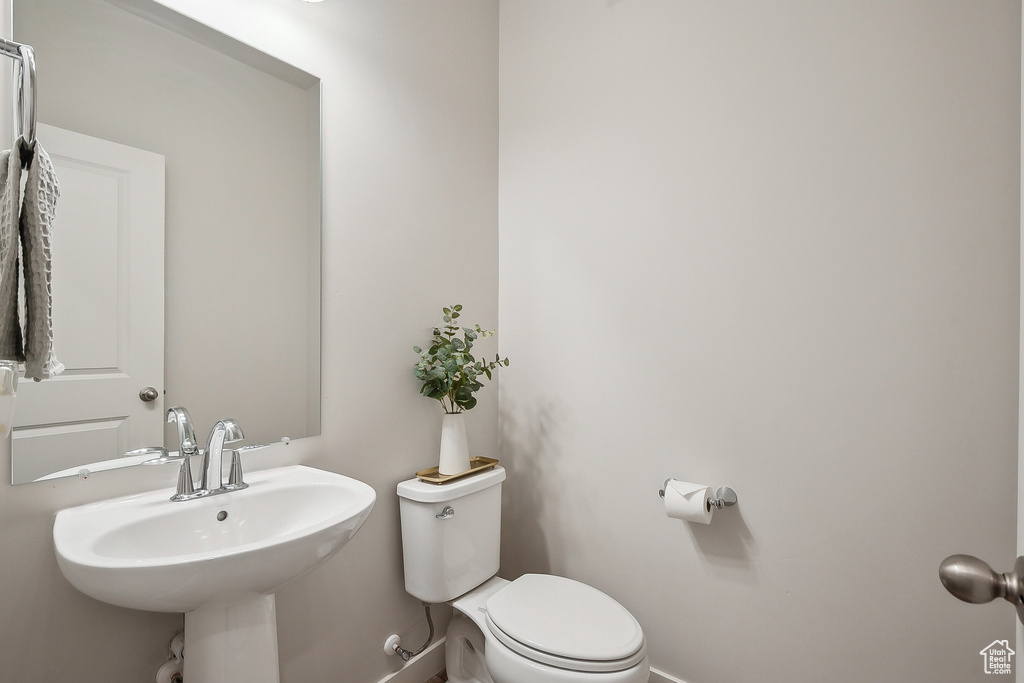 Bathroom featuring baseboards, toilet, and a sink