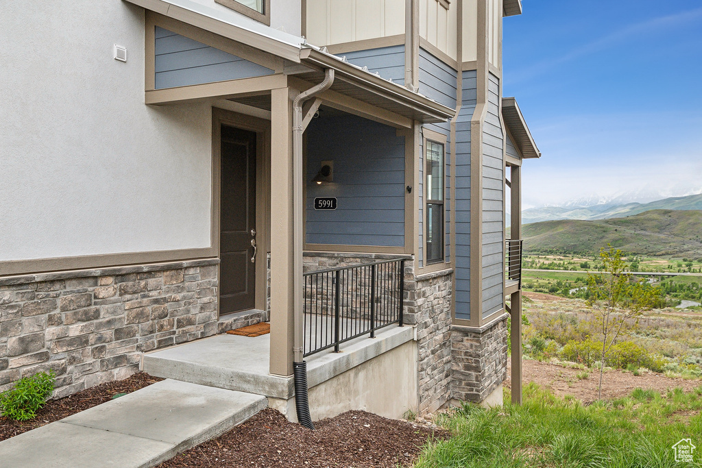 Entrance to property featuring stone siding, a mountain view, and a porch