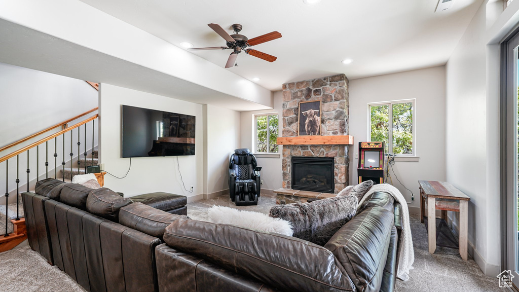 Carpeted living room with healthy amount of natural light, a ceiling fan, a stone fireplace, stairs, and recessed lighting