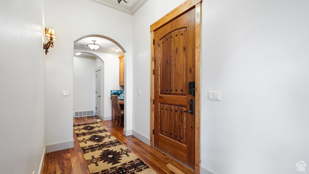 Entryway with crown molding, arched walkways, light wood-type flooring, and baseboards