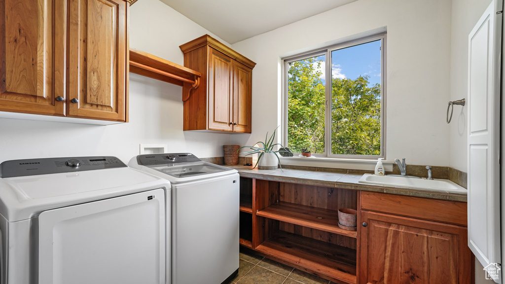 Laundry area with cabinet space, washer and clothes dryer, healthy amount of natural light, and dark tile patterned floors