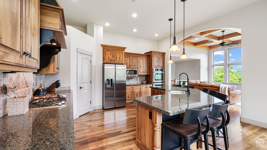 Kitchen with appliances with stainless steel finishes, coffered ceiling, a sink, light wood-style flooring, and recessed lighting