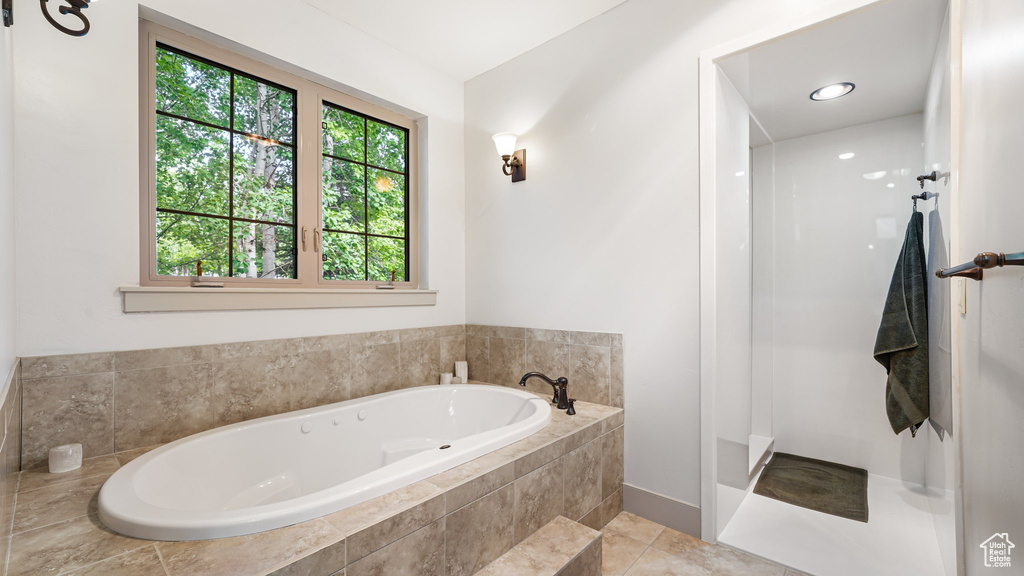 Full bath featuring a bath, walk in shower, baseboards, and tile patterned floors