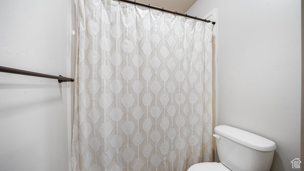 Bathroom featuring toilet and curtained shower