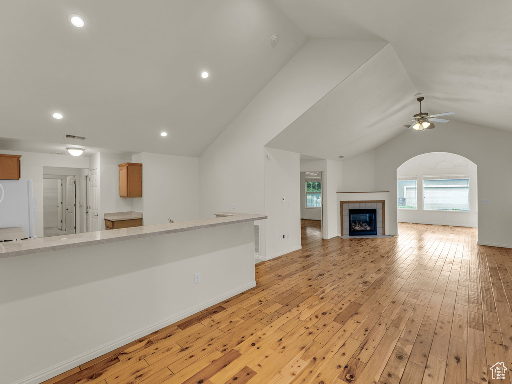 Unfurnished living room with lofted ceiling, light wood-style flooring, a tile fireplace, recessed lighting, and ceiling fan
