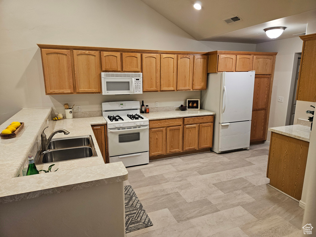 Kitchen featuring white appliances, light countertops, high vaulted ceiling, and brown cabinets