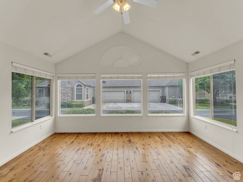 Unfurnished sunroom featuring a ceiling fan, hardwood / wood-style flooring, lofted ceiling, and baseboards