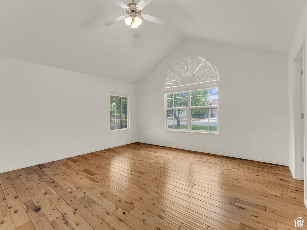 Unfurnished room with lofted ceiling, light wood-type flooring, a ceiling fan, and baseboards