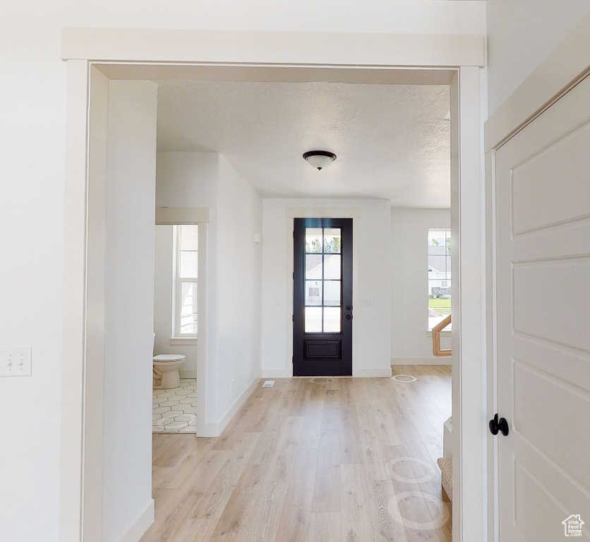 Entryway featuring light wood finished floors, plenty of natural light, baseboards, and a textured ceiling