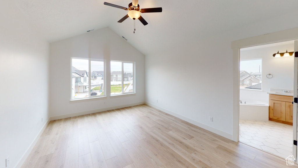 Unfurnished bedroom featuring light wood finished floors, vaulted ceiling, connected bathroom, ceiling fan, and a sink